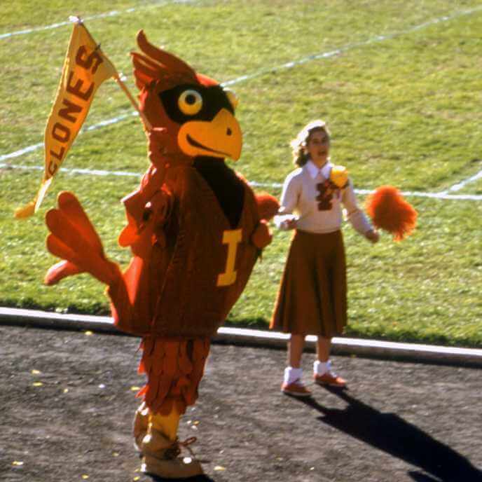 Cy holding a Cyclones pennant next to a cheerleader